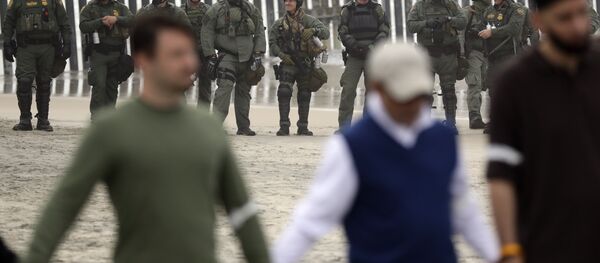 Border Patrol agents look on as a people hold hands and pray during a protest Monday, Dec. 10, 2018, in San Diego - Sputnik International