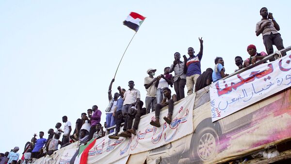Demonstrators wave their national flag as they attend a protest rally demanding Sudanese President Omar Al-Bashir to step down outside Defence Ministry in Khartoum, Sudan April 10, 2019. - Sputnik International