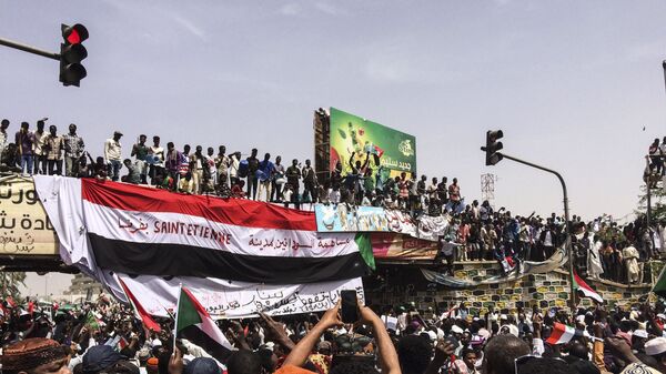 Demonstrators gather in Sudan's capital of Khartoum, Friday, April 12, 2019. The Sudanese protest movement has rejected the military's declaration that it has no ambitions to hold the reins of power for long after ousting the president of 30 years, Omar al-Bashir. The writing on the Sudanese flag says With the participation of the Sudanese in Saint Etienne, France. - Sputnik International