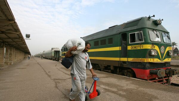 An Iraqi passenger carries his belongings next to a train at the al-Alawi railway station, central Baghdad, Iraq - Sputnik International