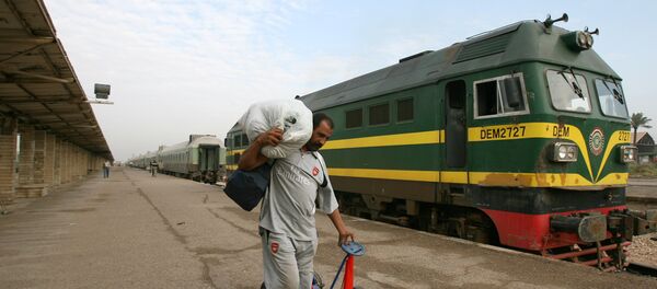 An Iraqi passenger carries his belongings next to a train at the al-Alawi railway station, central Baghdad, Iraq - Sputnik International