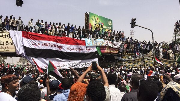 Demonstrators gather in Sudan's capital of Khartoum, Friday, April 12, 2019. The Sudanese protest movement has rejected the military's declaration that it has no ambitions to hold the reins of power for long after ousting the president of 30 years, Omar al-Bashir. The writing on the Sudanese flag says 'With the participation of the Sudanese in Saint Etienne, France.' - Sputnik International