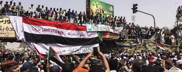 Demonstrators gather in Sudan's capital of Khartoum, Friday, April 12, 2019. The Sudanese protest movement has rejected the military's declaration that it has no ambitions to hold the reins of power for long after ousting the president of 30 years, Omar al-Bashir. The writing on the Sudanese flag says 'With the participation of the Sudanese in Saint Etienne, France.' - Sputnik International