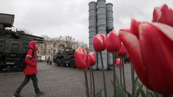 A visitor approaches a surface-to-air missile system S-400 Triumph during an exhibition displaying Russian military equipment, vehicles and weapons, with tulips seen in the foreground, in the Black Sea port of Sevastopol, Crimea April 12, 2019 - Sputnik International