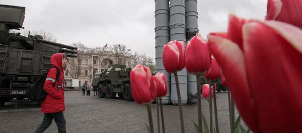 A visitor approaches a surface-to-air missile system S-400 Triumph during an exhibition displaying Russian military equipment, vehicles and weapons, with tulips seen in the foreground, in the Black Sea port of Sevastopol, Crimea April 12, 2019 - Sputnik International