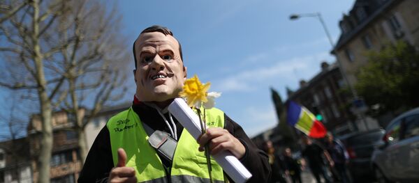 A demonstrator sporting a mask representing French President Emmanuel Macron holds a yellow flower during yellow vest protests, in Rouen on April 6, 2019 - Sputnik International