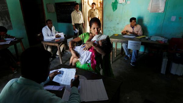 A woman struggles to hold her daughter as she waits to collect her voter slip at a polling station during the first phase of general election in Majuli, a large river island in the Brahmaputra river, in the northeastern Indian state of Assam, India April 11, 2019 - Sputnik International