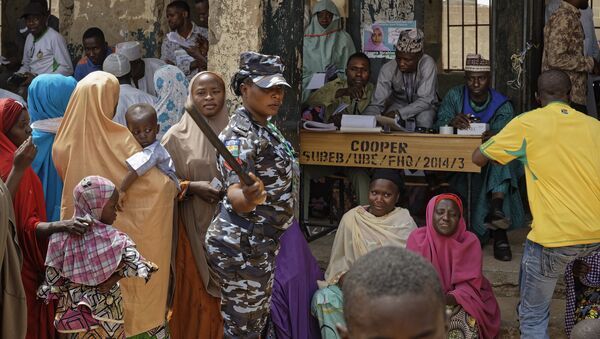 A policewoman chases away children as women queue in the midday sun to cast their votes at a polling station in Kano, northern Nigeria Saturday, Feb. 23, 2019. Nigerians are going to the polls for a presidential election Saturday, one week after a surprise delay for Africa's largest democracy. - Sputnik International
