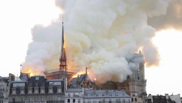 Smoke and flames rise during a fire at the landmark Notre-Dame Cathedral in central Paris on April 15, 2019, potentially involving renovation works being carried out at the site, the fire service said. - Sputnik International