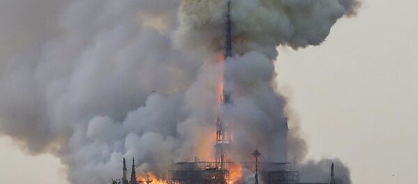 Flames and smoke are seen billowing from the roof at Notre-Dame Cathedral in Paris on April 15, 2019. A fire broke out at the landmark Notre-Dame Cathedral in central Paris, potentially involving renovation works being carried out at the site, the fire service said. - Sputnik International