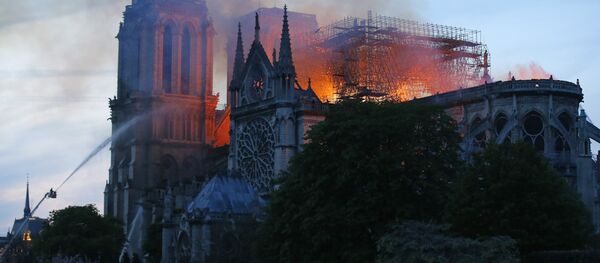 A firefighter tackles the blaze as flames and smoke rise from Notre Dame cathedral as it burns in Paris, Monday, April 15, 2019. Massive plumes of yellow brown smoke is filling the air above Notre Dame Cathedral and ash is falling on tourists and others around the island that marks the center of Paris A firefighter tackles the blaze as flames and smoke rise from Notre Dame cathedral as it burns in Paris, Monday, April 15, 2019. Massive plumes of yellow brown smoke is filling the air above Notre Dame Cathedral and ash is falling on tourists and others around the island that marks the center of Paris - Sputnik International
