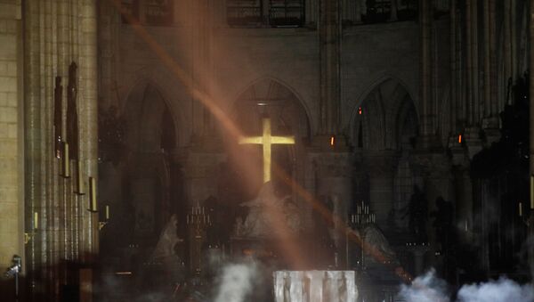 Smoke rises around the alter in front of the cross inside the Notre Dame Cathedral as a fire continues to burn in Paris, France, April 16, 2019. - Sputnik International