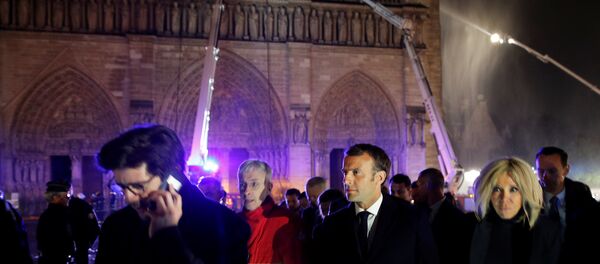 French President Emmanuel Macron and his wife Brigitte walk outside the Notre Dame Cathedral where a fire continues to burn in Paris on April 16, 2019. - Sputnik International