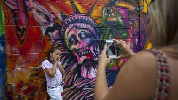 In this March 19, 2015 file photo, a girl poses for a picture in front of a mural depicting the statue of liberty as death, at Bolivar square in Caracas, Venezuela - Sputnik International