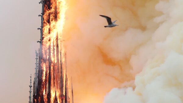 Smoke billows as fire engulfs the spire of Notre Dame Cathedral in Paris, France April 15, 2019 - Sputnik International