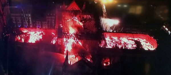 An image taken from a television screen shows an aerial view of the Notre Dame Cathedral engulfed in flames on 15 April, 2019, in the French capital Paris An image taken from a television screen shows an aerial view of the Notre Dame Cathedral engulfed in flames on 15 April, 2019, in the French capital Paris - Sputnik International
