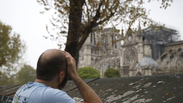 Man holds his head while watching the Notre Dame cathedral after the fire in Paris, Tuesday, April 16, 2019 - Sputnik International