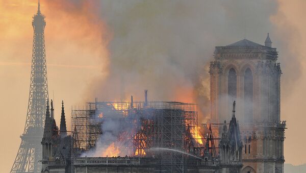 In this image made available on Tuesday April 16, 2019 flames and smoke rise from the blaze after the spire toppled over on Notre Dame cathedral in Paris, Monday, April 15, 2019 - Sputnik International