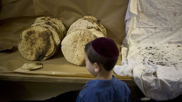A boy looks at matzo, a traditional handmade Passover unleavened bread, that Jewish Orthodox bakers made in a bakery - Sputnik International