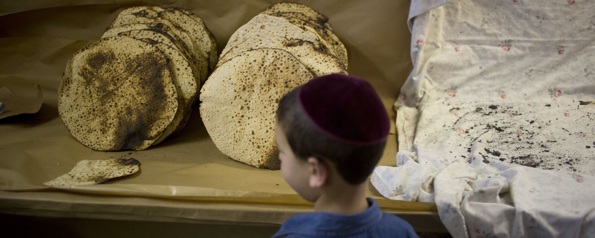 A boy looks at matzo, a traditional handmade Passover unleavened bread, that Jewish Orthodox bakers made in a bakery - Sputnik International, 1920, 19.03.2021