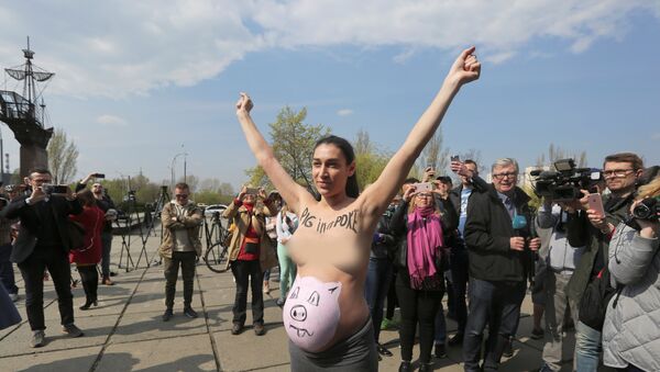 A topless activist of women's rights group Femen protests outside a polling station during the visit of Ukrainian presidential candidate Volodymyr Zelenskiy, who takes part in the second round of a presidential election in Kiev, Ukraine April 21, 2019. - Sputnik International