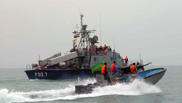 A picture released by the official Iranian News Agency shows members of Iran's elite Revolutionary Guard riding their boat along with an Iranian naval vessel during manoeuvers along the Gulf Sea and Sea of Oman, 03 April 2006 - Sputnik International