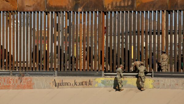 U.S. soldiers walk next to the border fence between Mexico and the United States, as migrants are seen walking behind the fence, after crossing illegally into the U.S. to turn themselves in, in El Paso, Texas, U.S., in this picture taken from Ciudad Juarez, Mexico, April 3, 2019 - Sputnik International
