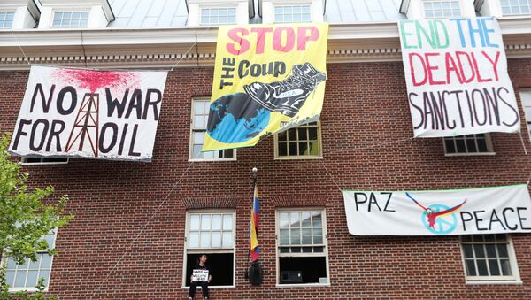 An activist in opposition of the U.S. involvement in Venezuela occupying the Venezuelan Embassy, sits in a window sill in Washington, U.S., April 25, 2019. - Sputnik International
