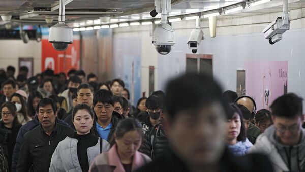 Commuters walk by surveillance cameras installed at a walkway in between two subway stations in Beijing, Tuesday, Feb. 26, 2019 - Sputnik International