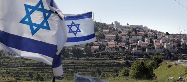 A photo taken on April 12, 2019 shows Israeli flags in front of a partial view of the Israeli settlement of Efrat situated on the southern outskirts of the West Bank city of Bethlehem - Sputnik International