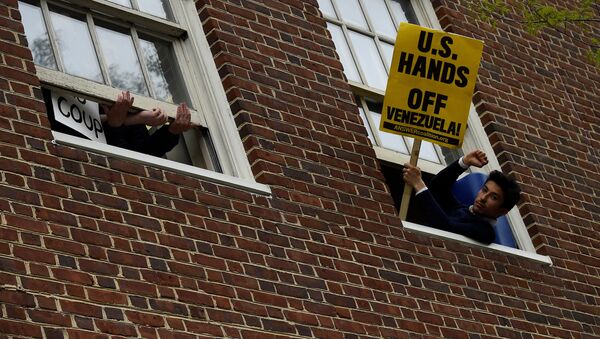 A man holds a sign outside the window of the Venezuelan embassy which is occupied by Nicolas Maduro supporters as Venezuelan opposition leader Juan Guido's envoy to the United States Carlos Vecchio speaks outside in Washington, U.S., May 1, 2019 - Sputnik International