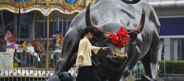 A woman pulls a 2 wheel trolley loaded with goods touches a bull statue on display outside a retail and wholesale clothing mall in Beijing, Monday, July 9, 2018 A woman pulls a 2 wheel trolley loaded with goods touches a bull statue on display outside a retail and wholesale clothing mall in Beijing, Monday, July 9, 2018 - Sputnik International