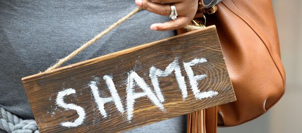 Chandra Craven, 42, dressed as Septa Unella, holds a shame sign from the show while waiting in line at a HBO Game of Thrones final season promotional event at Primark Boston where people could sit in a replica of the Iron Throne from the show on Friday April 19, 2019 in Boston, Ma. - Sputnik International
