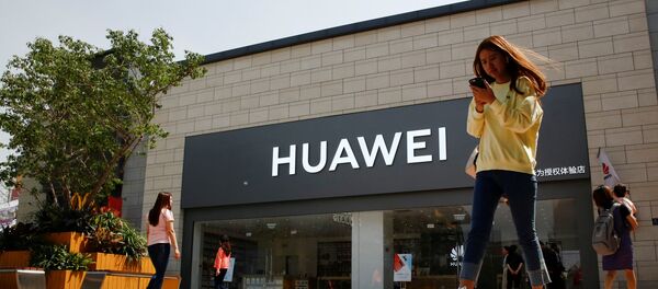 A woman looks at her phone as she walks past a Huawei shop in Beijing, China May 16, 2019 A woman looks at her phone as she walks past a Huawei shop in Beijing, China May 16, 2019 - Sputnik International