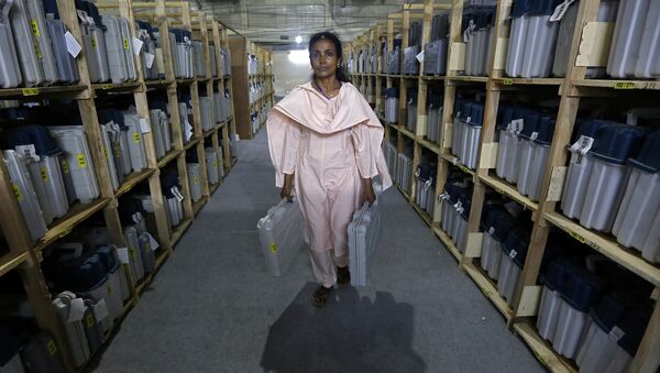 An election staff member carries Electronic Voting Machines (EVM) after collecting them from a distribution centre at an indoor stadium ahead of the seventh and last phase of general election, in Kolkata, India, May 18, 2019 - Sputnik International