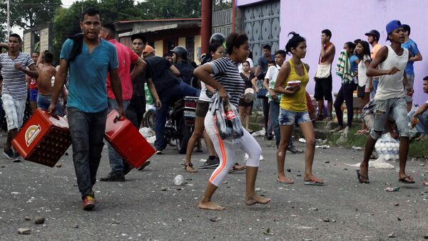 People carry goods taken from a food wholesaler after it was broken into, in La Fria, Venezuela December 17, 2016. REUTERS/Carlos Eduardo Ramirez - Sputnik International