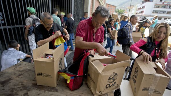 In this July 6, 2018 photo, employees of a government-supported cultural center collect their boxes with subsided food distributed under government program named CLAP in downtown Caracas, Venezuela. Everyone from museum curators to janitors waited in line to sign a clipboard before government loyalists hand over the box of food. - Sputnik International