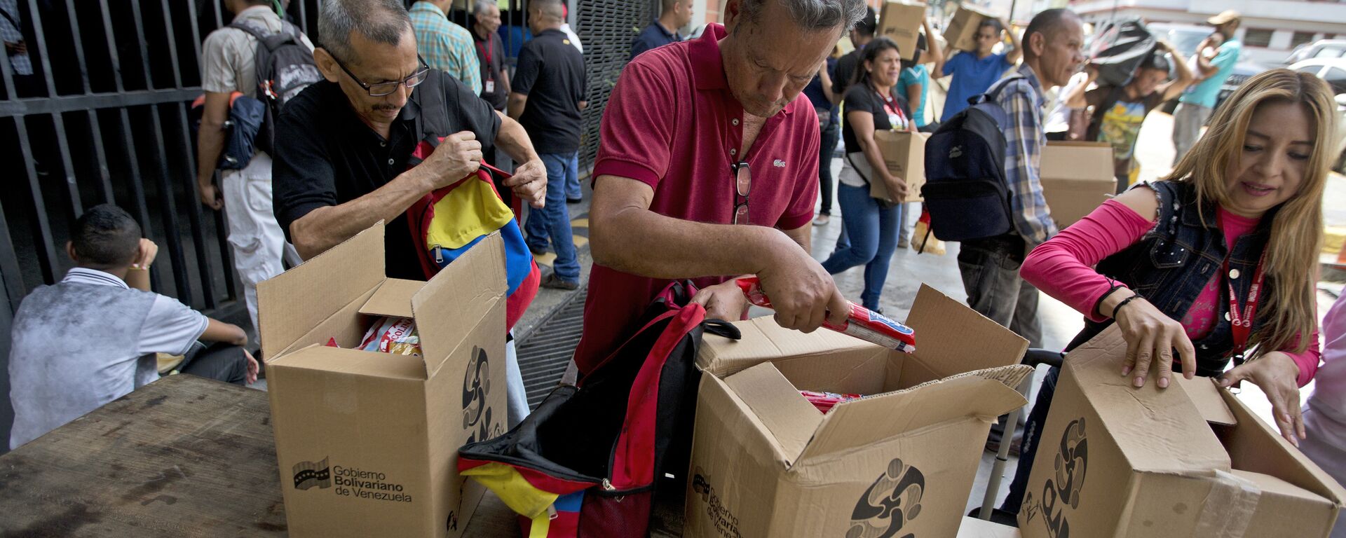 In this July 6, 2018 photo, employees of a government-supported cultural center collect their boxes with subsided food distributed under government program named CLAP in downtown Caracas, Venezuela. Everyone from museum curators to janitors waited in line to sign a clipboard before government loyalists hand over the box of food. - Sputnik International, 1920, 17.06.2021