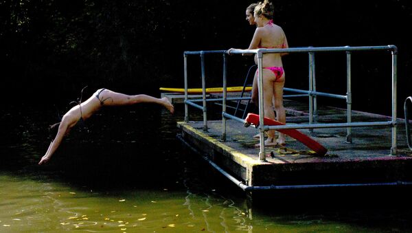 A woman dives into the cold water of the mixed pond during unseasonal hot weather on Hampstead Heath in London, Thursday, Sept. 28, 2011 - Sputnik International