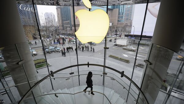 A customer walks under an Apple logo sign at an Apple shop in Shanghai on February 22, 2012 - Sputnik International