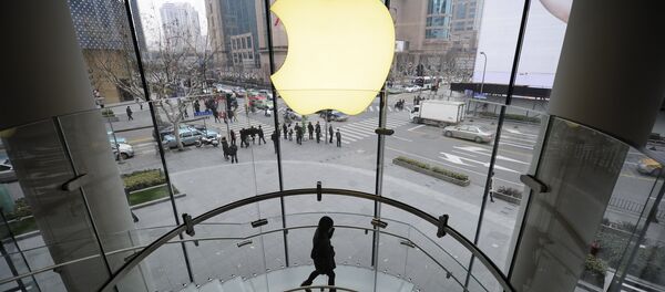 A customer walks under an Apple logo sign at an Apple shop in Shanghai on February 22, 2012 - Sputnik International