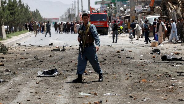 An Afghan policeman stands guard at the site of a suicide attack while others remove a wreckage of a car hit in the attack in Kabul, Afghanistan May 31, 2019. - Sputnik International