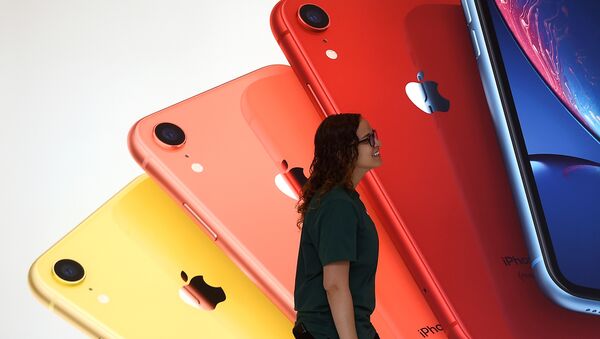 An Apple Store employee walks past an illustration of iPhones at the new Apple Carnegie Library during the grand opening and media preview in Washington, U.S., May 9, 2019 - Sputnik International