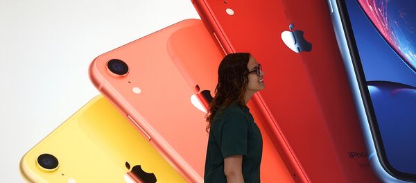 An Apple Store employee walks past an illustration of iPhones at the new Apple Carnegie Library during the grand opening and media preview in Washington, U.S., May 9, 2019 - Sputnik International
