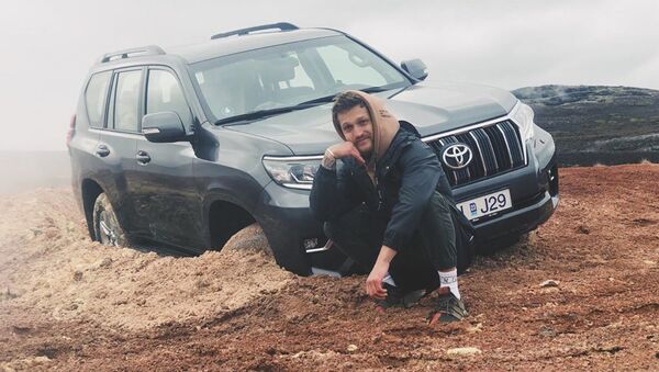 Alexander Tikhomirov, a Russian lifestyle blogger, poses near the off-roader stuck in clay - Sputnik International