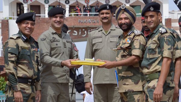 Pakistani Wing Commander Bilal (C) presents sweets to Indian Border Security Force (BSF) Deputy Inspector General JS Oberoi (2R) on the occasion of the Eid al-Fitr festival which marks the end of the holy month of Ramadan, at the India Pakistan Wagah Border Post, about 35 kms from Amritsar on July 6, 2016 - Sputnik International
