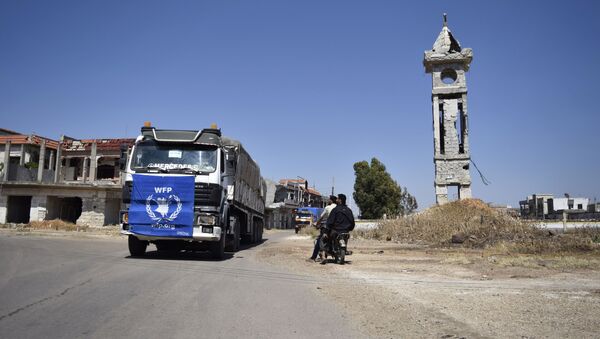 An aid truck of the UN World Food Programm (WFP) drives past destroyed buildings the town of Al-Houla, on the northern outskirts of Homs in central Syria, on May 25, 2016 - Sputnik International