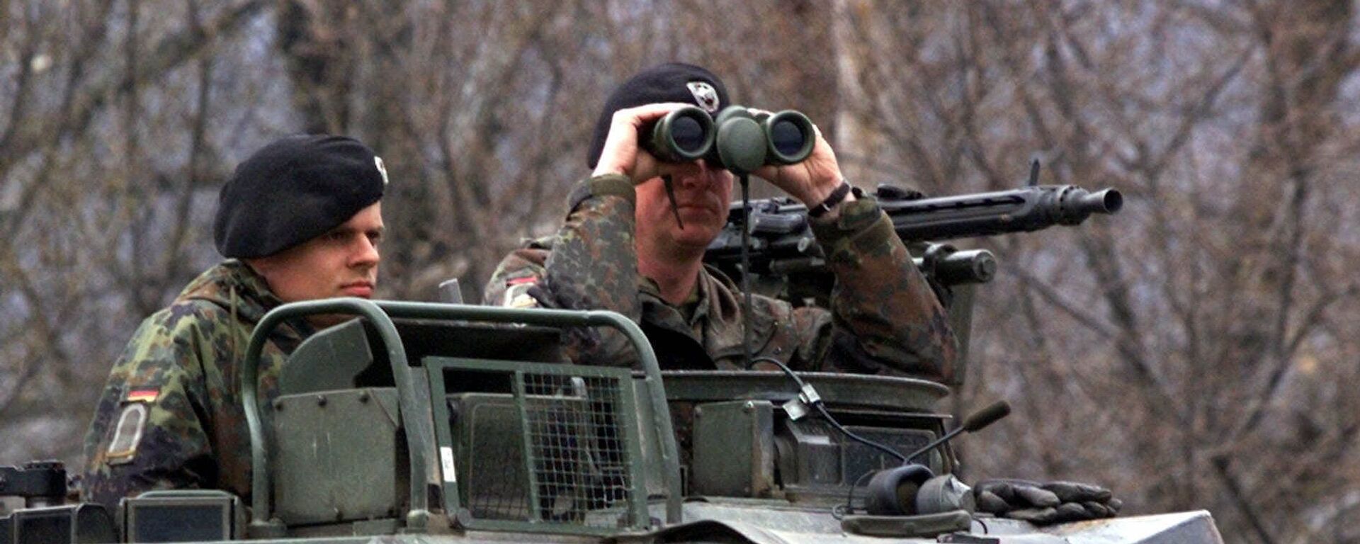 A German officer of the NATO contingent deployed in Macedonia looks through his binoculars - Sputnik International, 1920, 08.05.2023