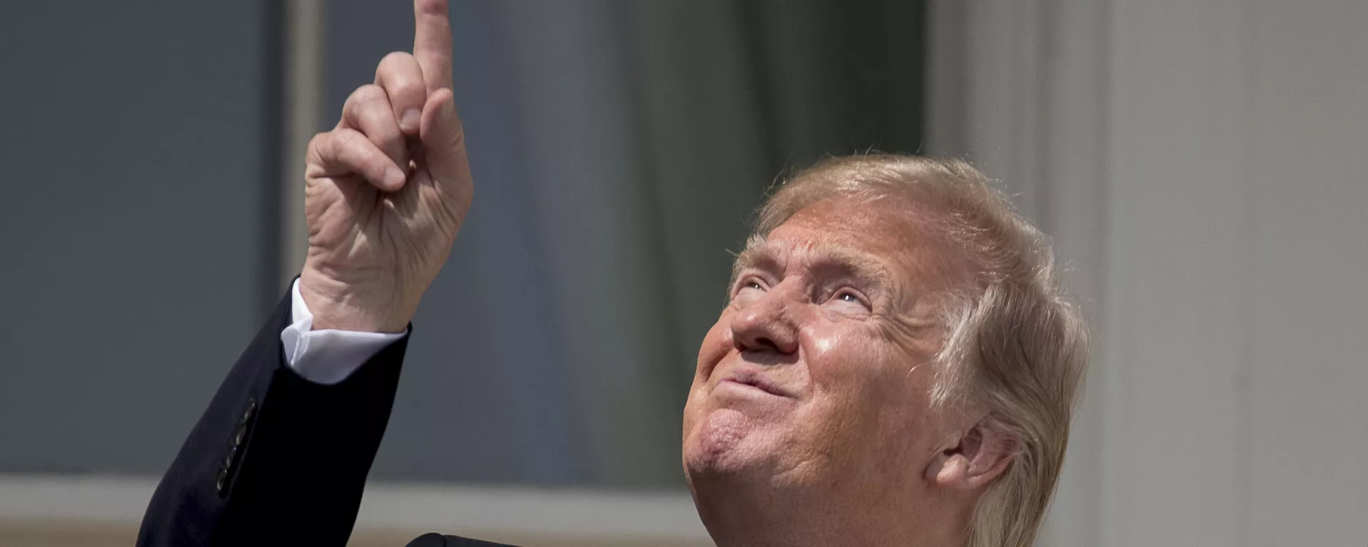 El presidente Donald Trump señala el sol cuando llega para ver el eclipse solar, el lunes 21 de agosto de 2017, en la Casa Blanca en Washington. - Sputnik Internacional, 1920, 23.01.2024