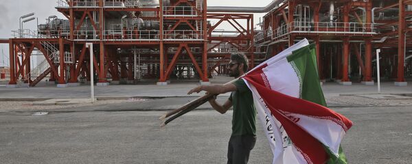 An Iranian worker carries Iranian flags prior to an inauguration ceremony of a natural gas refinery at the South Pars gas field on the northern coast of the Persian Gulf, in Asaluyeh, Iran An Iranian worker carries Iranian flags prior to an inauguration ceremony of a natural gas refinery at the South Pars gas field on the northern coast of the Persian Gulf, in Asaluyeh, Iran - Sputnik International